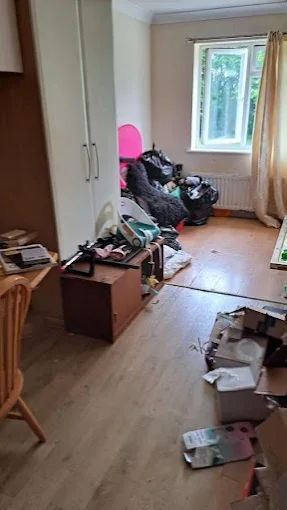 Cluttered bedroom full of boxes and bin bags before a house clearance