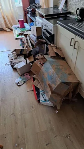 Kitchen floor covered in packaging and household waste before clearance